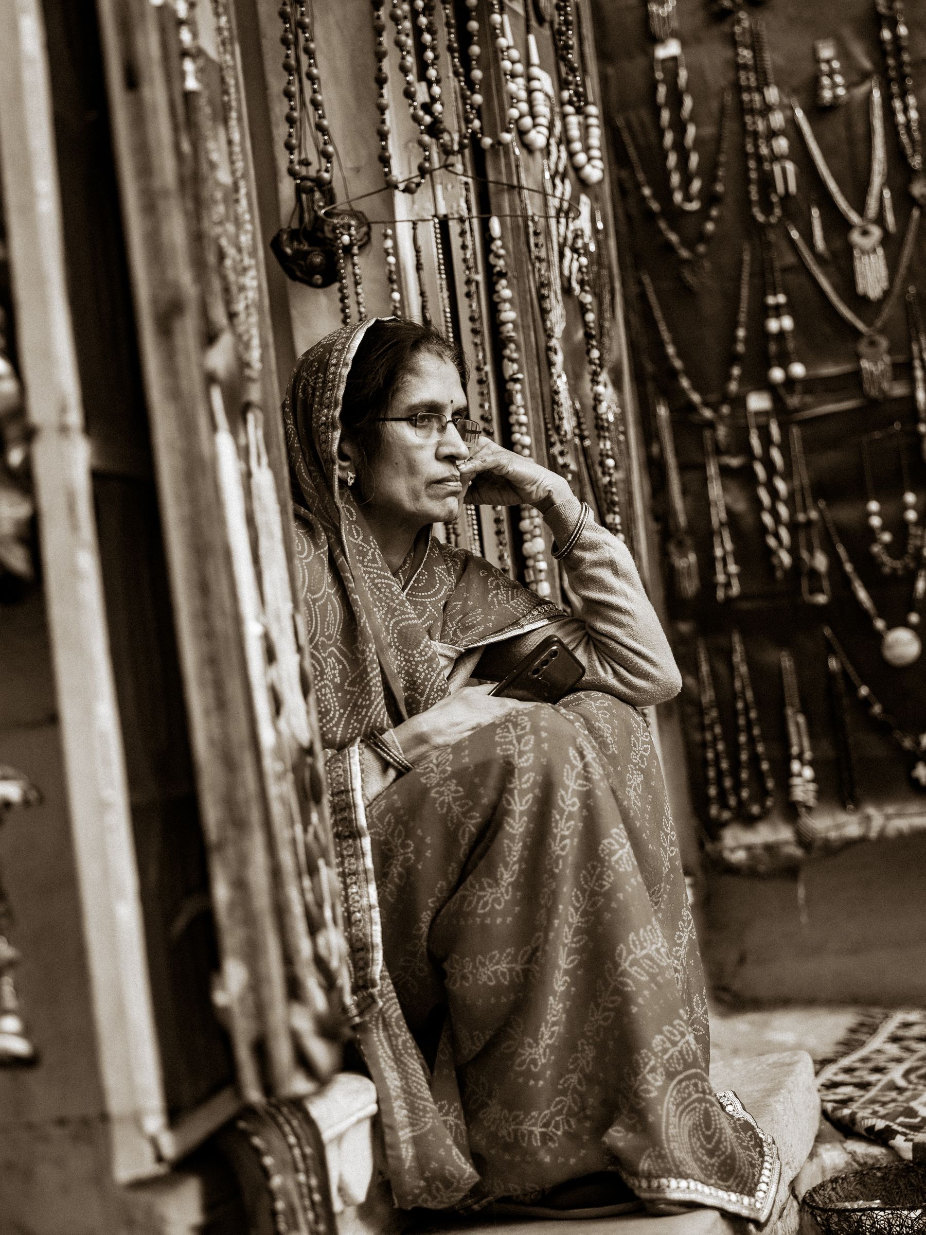 Woman Seated In Jewelry And Textile Shop In Black And White